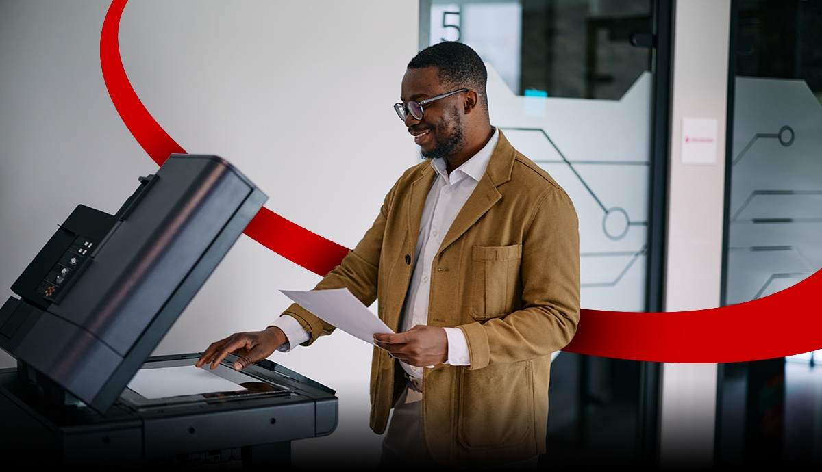 image of a man using a industrial printer in an office environment with a red orbital graphic intersecting behind him