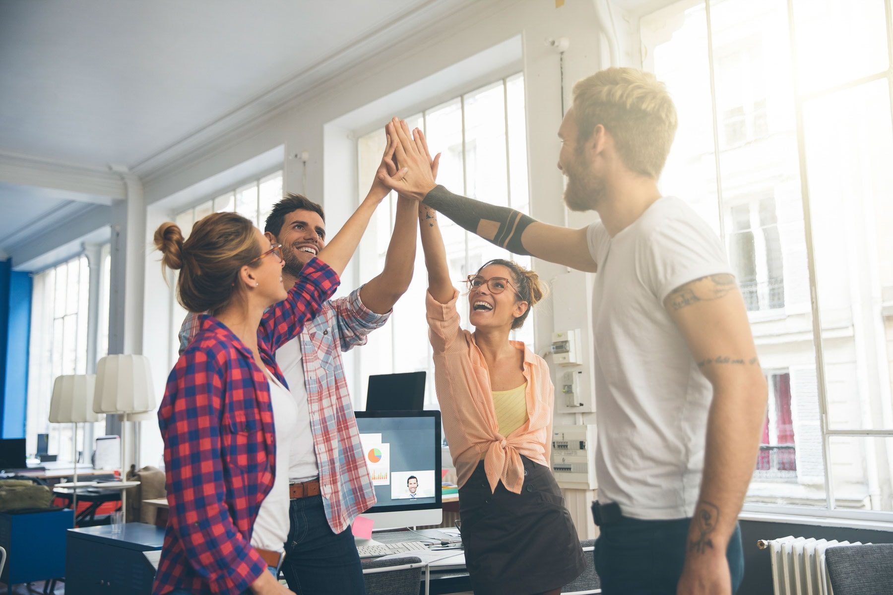 People celebrating in office and doing a high five.