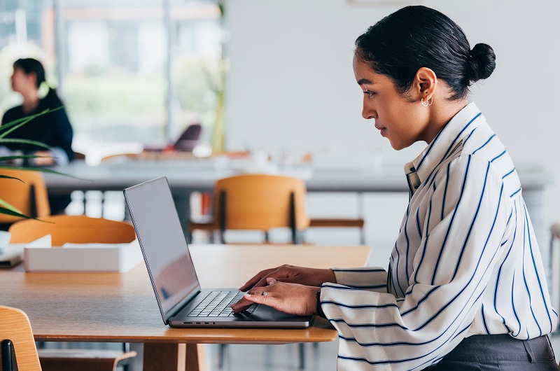 Professional typing on laptop in office workspace.