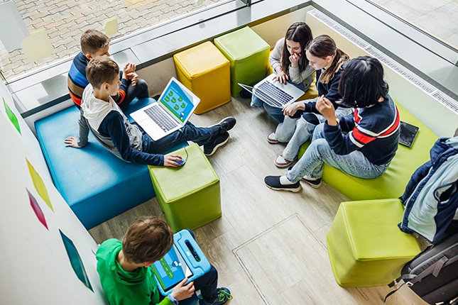 Young grade school students working on laptops in a modern collaborative learning environment.