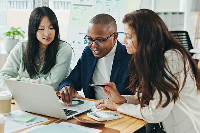 IT professionals collaborating on laptops to manage and optimize enterprise IT services with continuous support and reporting.