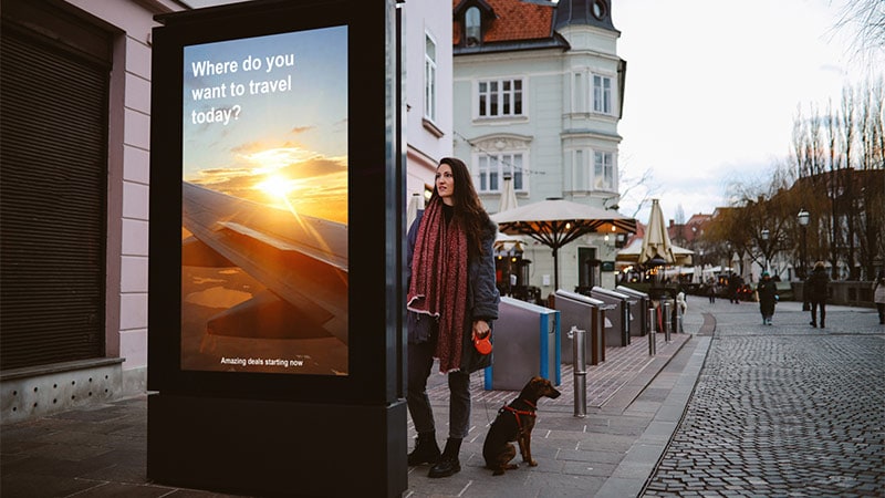 Woman looking at travel sign in a small down with her dog