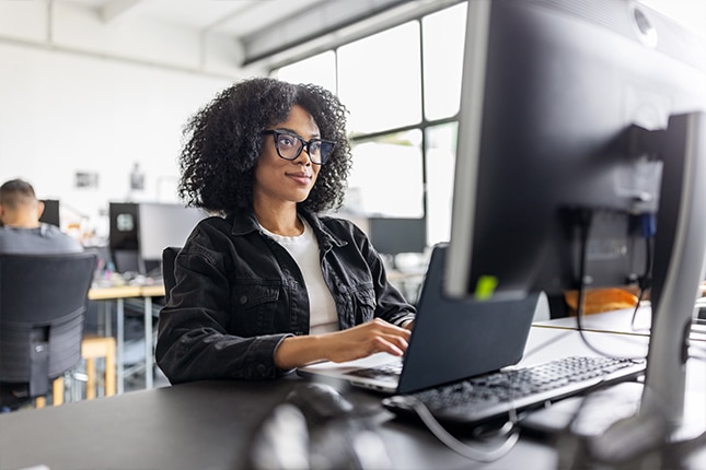 thumbnail image of a woman working on a desktop computer inside an office