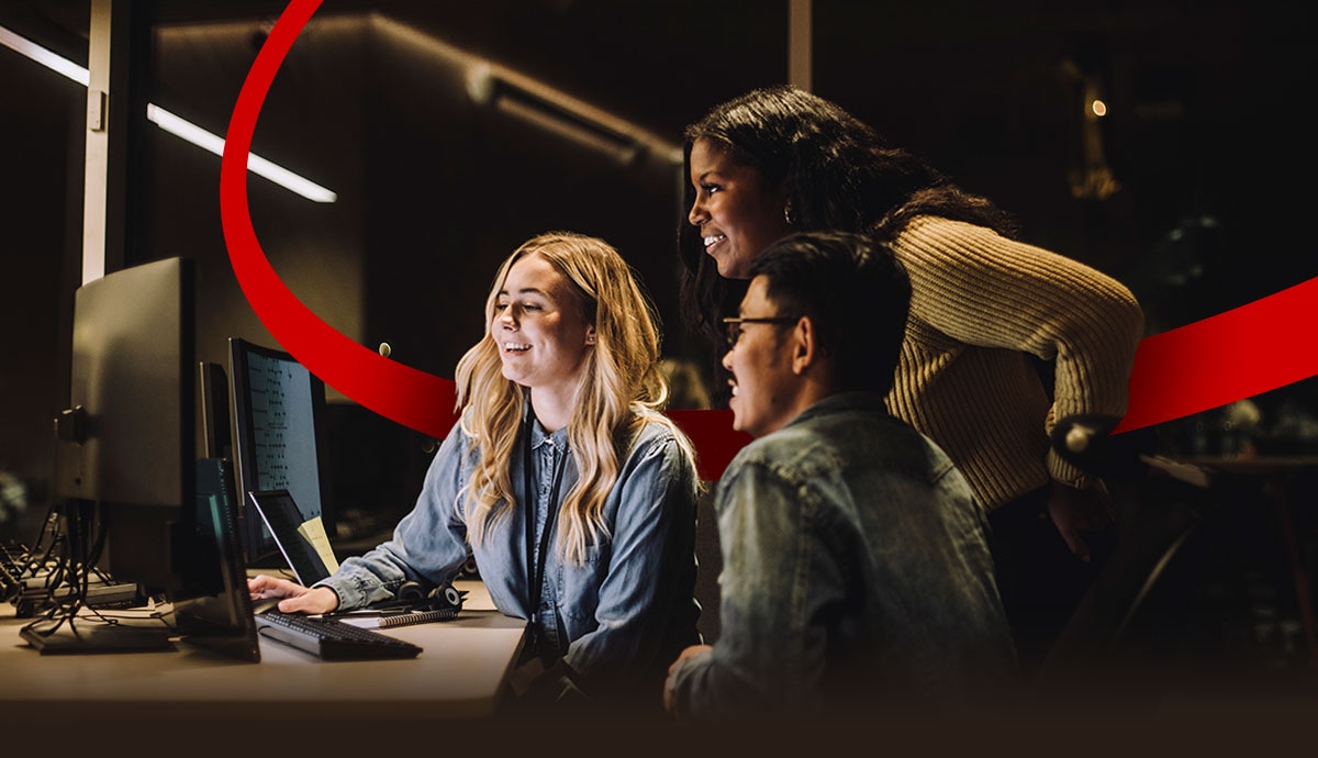 IT professionals collaborating at a workstation, reviewing data and monitoring systems in a modern office environment.