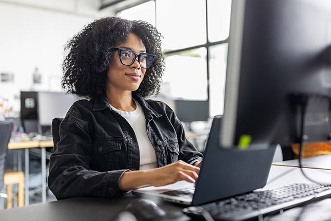 Compliance analyst using AI tools on a laptop to automate policy management and real-time gap analysis.