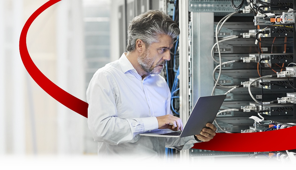 image of a man working in a data center holding a laptop computer
