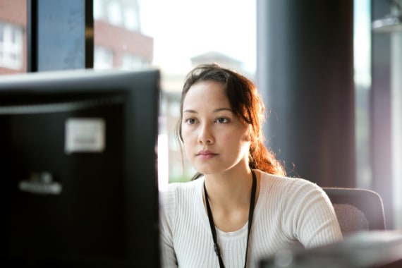 Female IT architect working in office staring at computer screen.