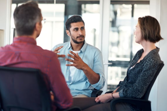Male IT professional discussing data management solutions with customers in a modern office.