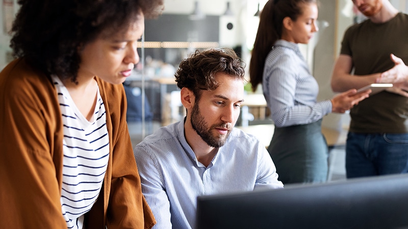 Two colleagues reviewing data privacy program together in office.