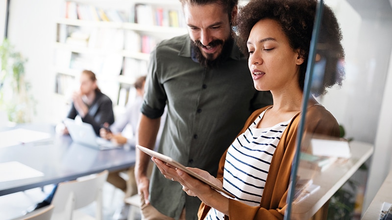 Colleagues reviewing work together in a hallway setting.