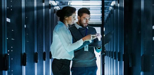 coworkers working on a laptop in a server room