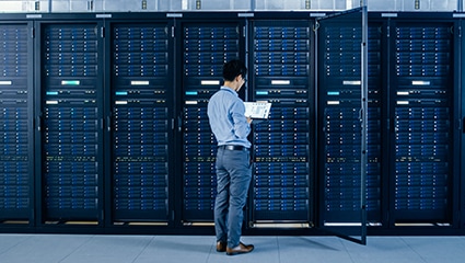 IT tech working in dark data center on a laptop.