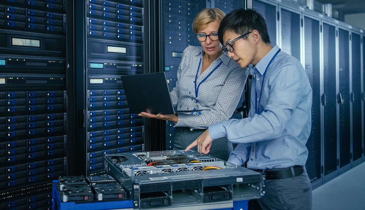 IT techs working on server in dark data center.