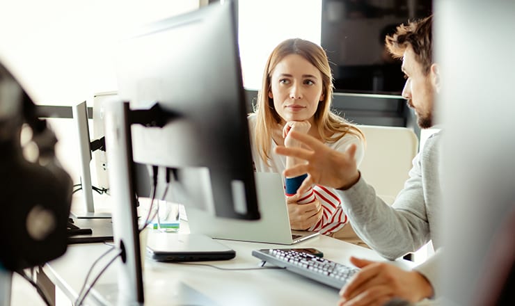 A man and woman discussing what is on a computer screen.