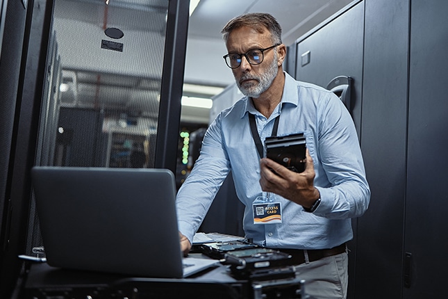 Government employee working on laptop in data center.