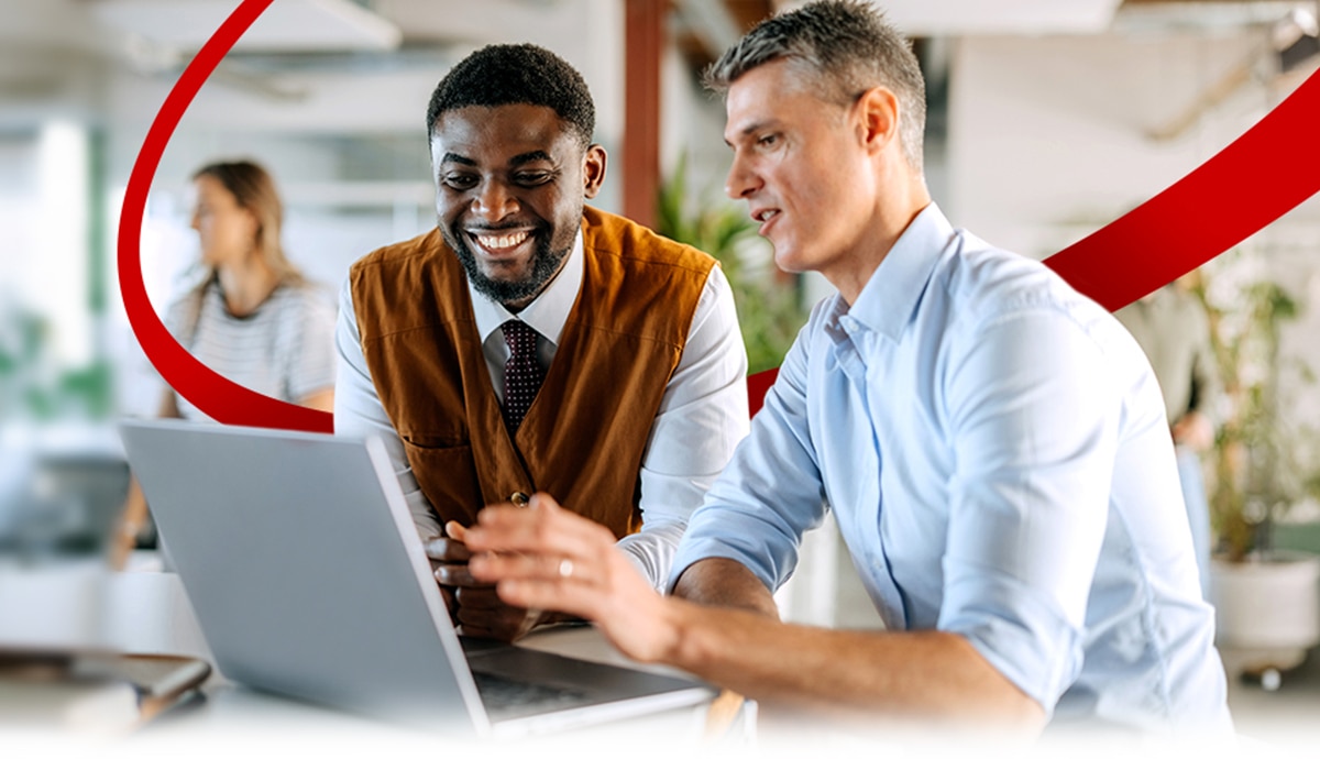 Two professionals collaborating over a laptop in a modern office environment.