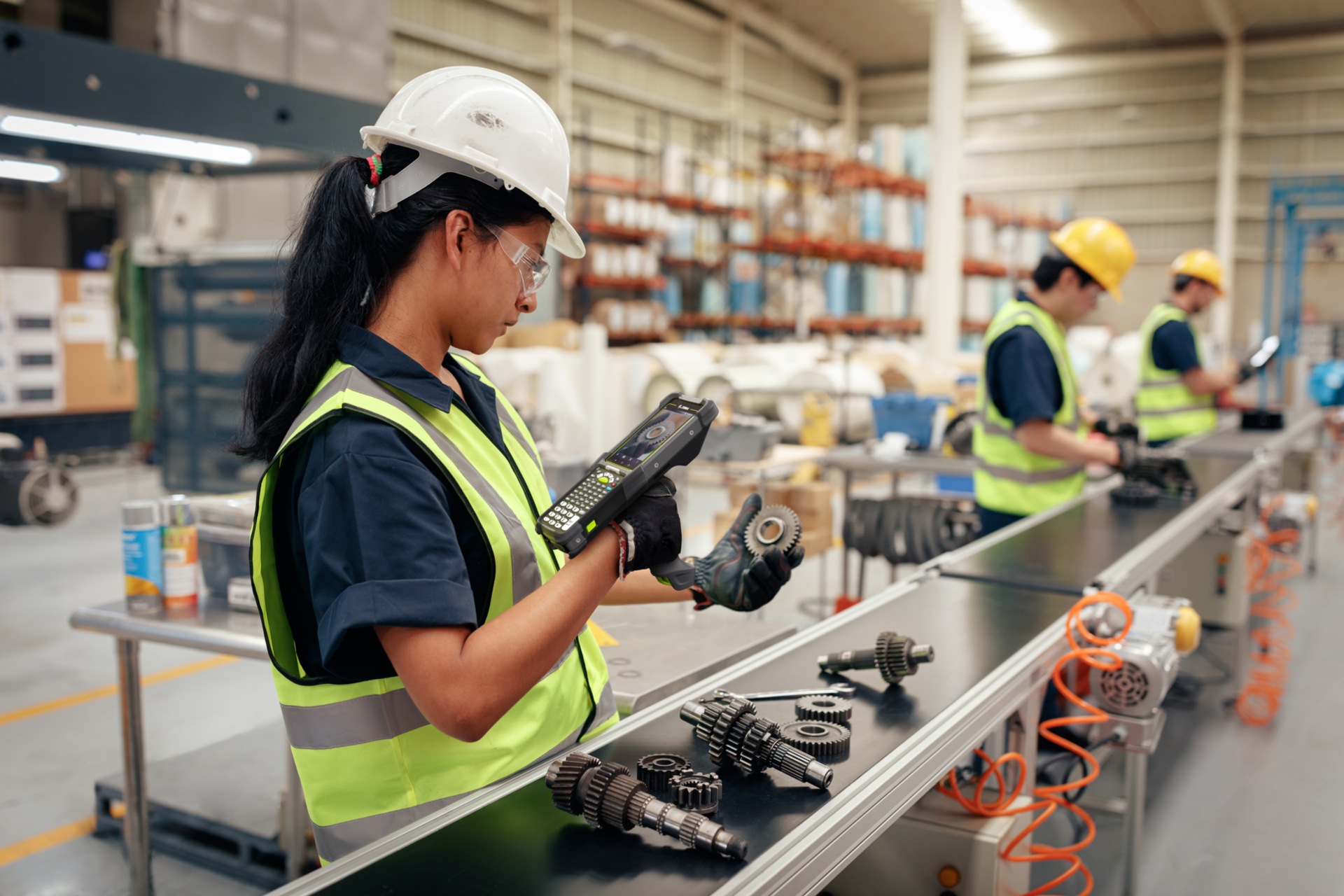 Lady working in a manufacturing facility scanning machine parts using a Zebra tool.