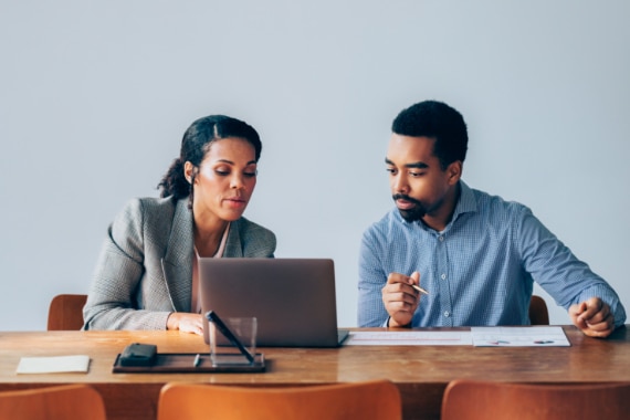 Two people collaborating in a meeting on a laptop.