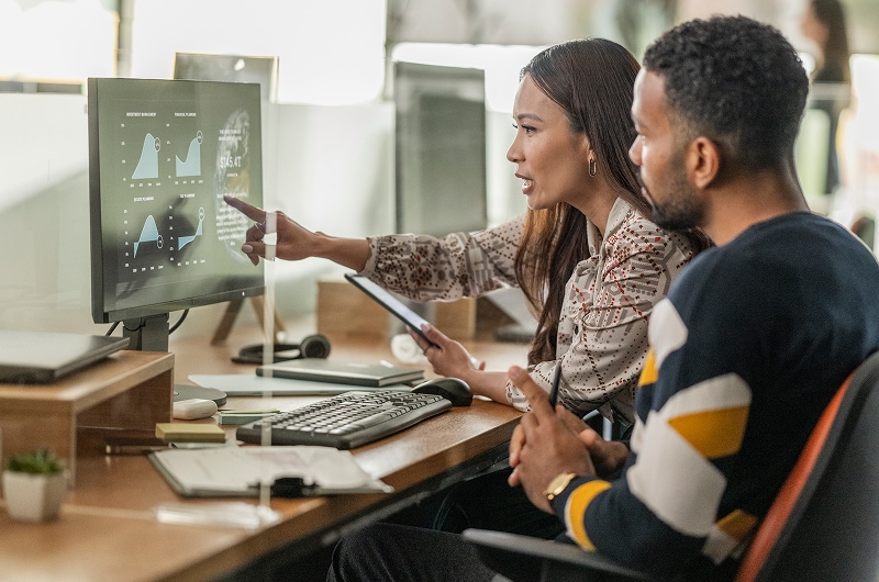 Coworkers collaborating at a computer workstation.
