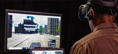 Man wearing a virtual-reality headset and looking at a computer monitor
