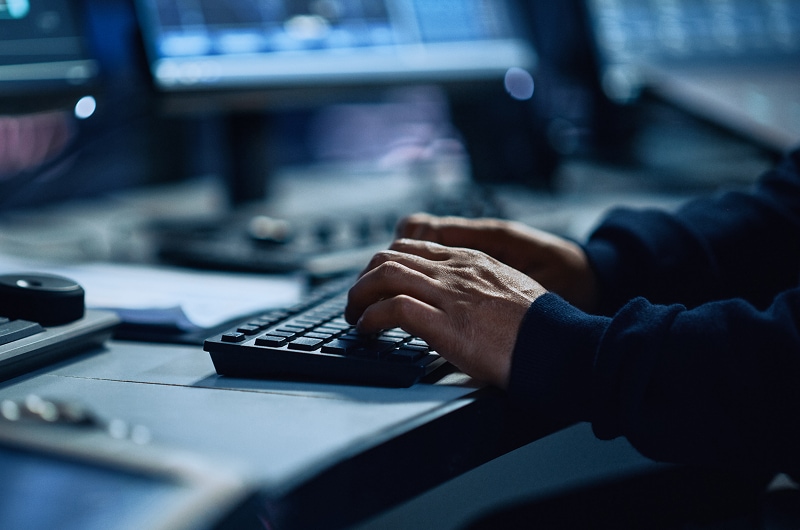 Close-up of hands typing on a computer keyboard in a work setting.
