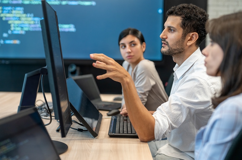 IT specialist collaborating with colleagues around a screen.
