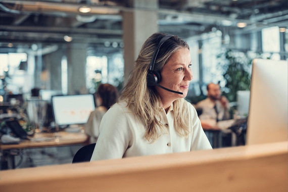 card thumbnail image of a woman working at a desktop computer wearing a headset