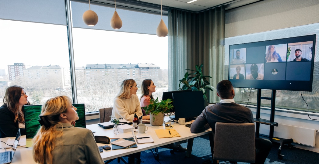 Coworkers working in a conference room with hybrid work tools