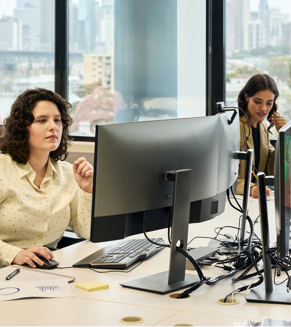 Two colleagues collaborating at a shared workstation in a bright modern office