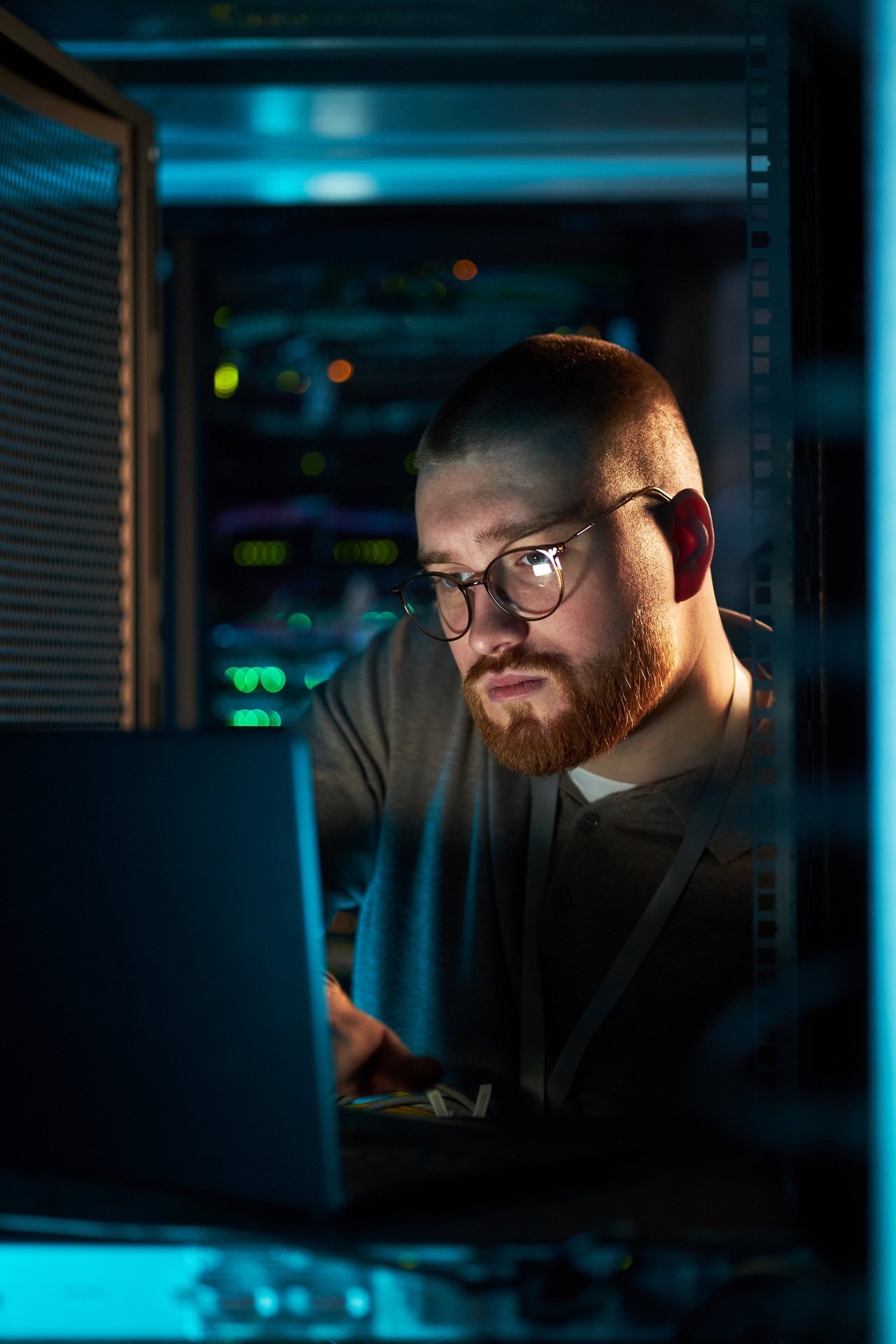 Engineer working on a laptop in a server room monitoring secure API integrations