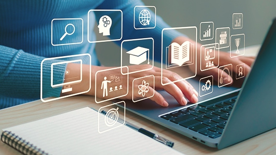 Person using laptop with school icons floating in the space.