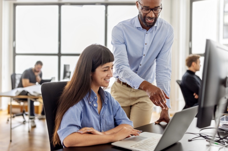 IT Specialist guiding colleague through a software setup on a laptop.