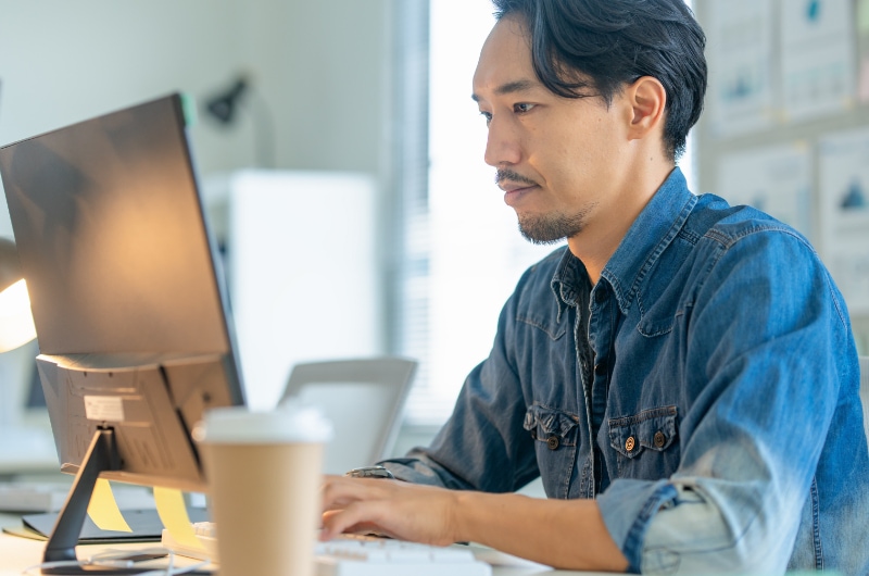 Developer focused on writing code at his desk in a modern office.
