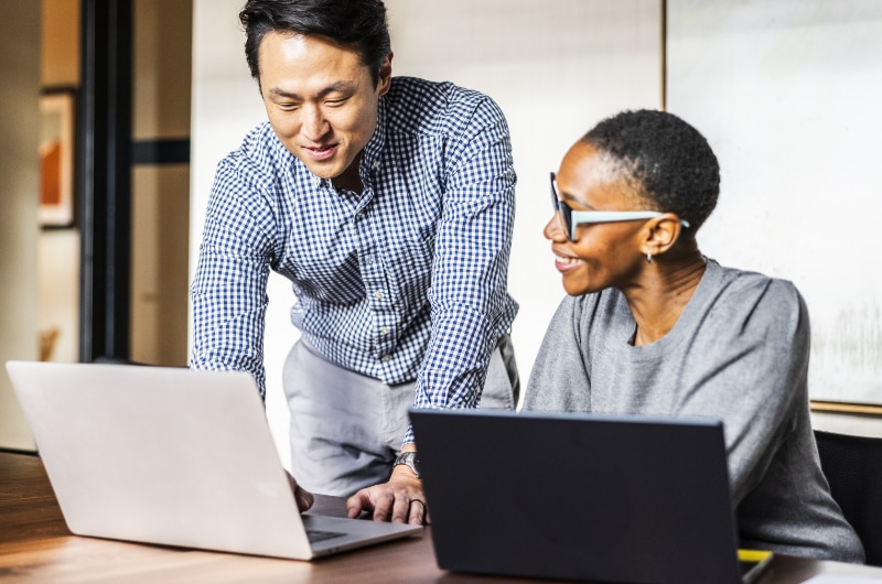 IT Specialist guiding colleague through a software setup on a laptop.