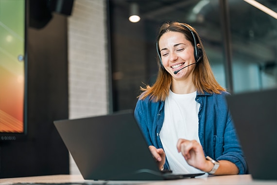 image of a woman on a headset working on a laptop computer in an office