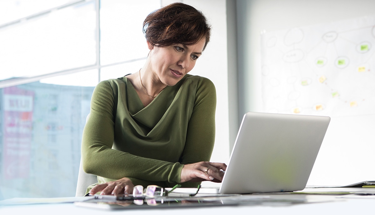 Woman working in front of a desktop computer in an office setting.