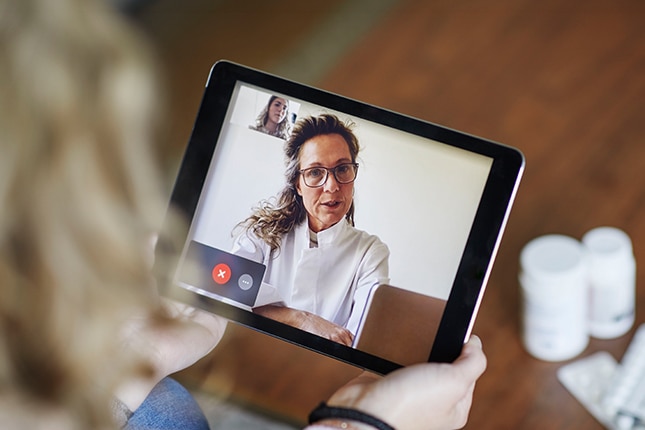 Virtual doctor appointment in person's home with doctor on tablet.