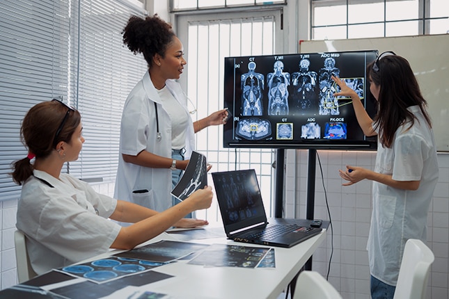 Nurses in a room using AI technology on a laptop.