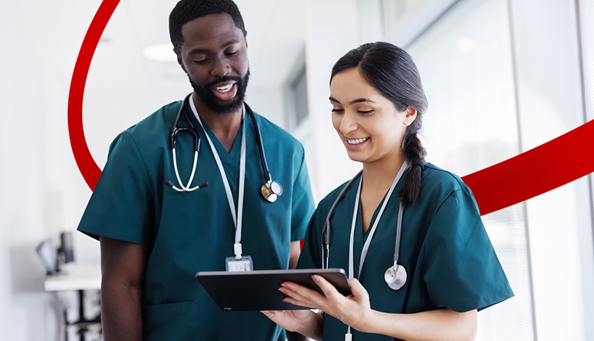 Two nurses using healthcare technology in a brightly lit hospital.