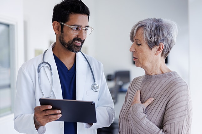 Doctor Discussing Health With Senior Patient in Hospital