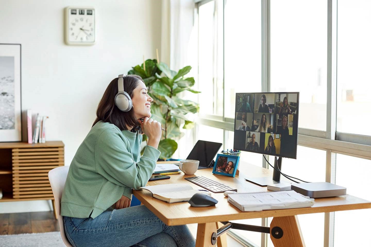 Une fille assise devant un ordinateur portant des écouteurs pendant qu’elle assiste à un appel vidéo de groupe.