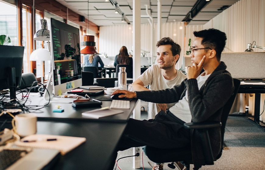 Male computer professionals programming on computer at tech-startup office