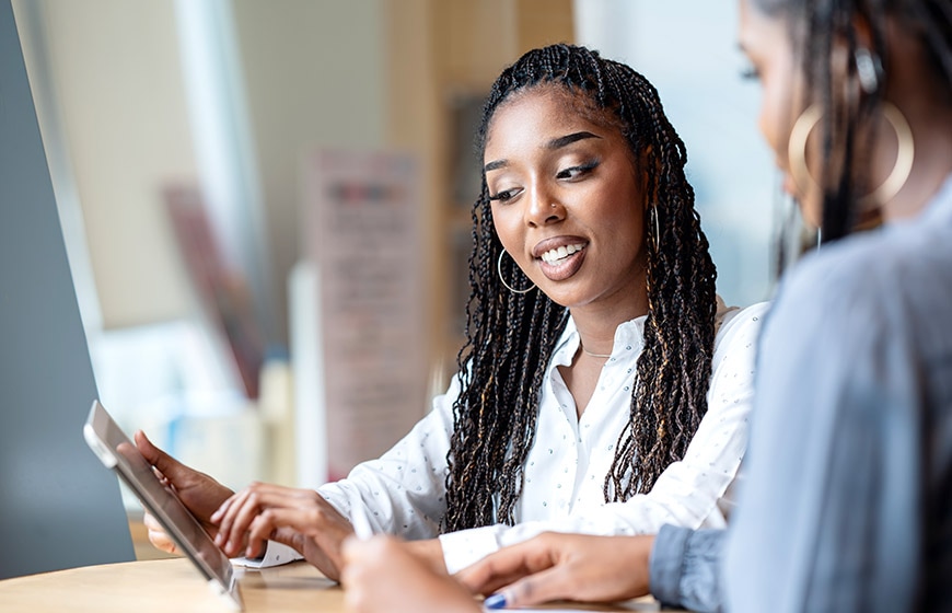 A female business development lead in a discussion with her team via a tablet computer in a tech business office.