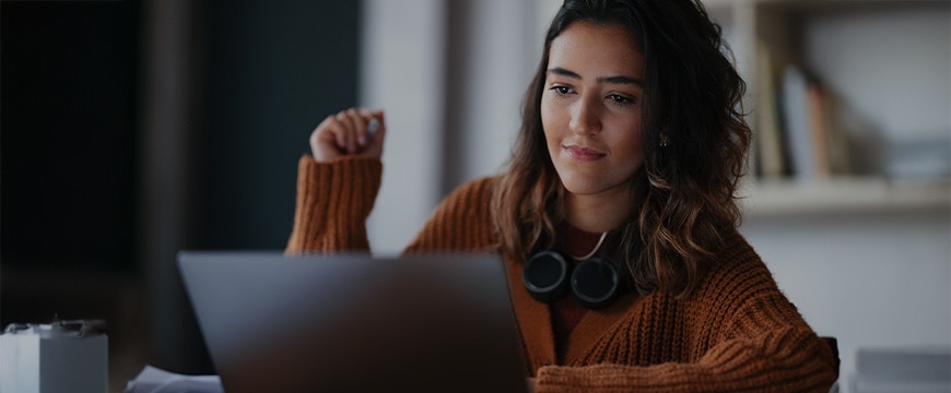 Young Woman Studying At Laptop in Cozy Setting With Books in Background