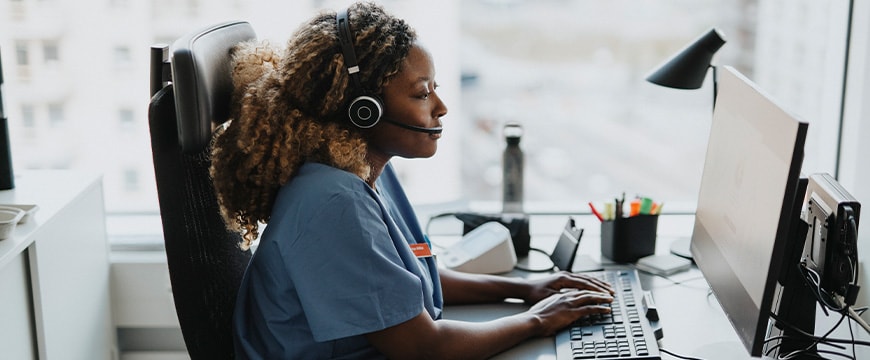 Side view of female medical worker working on computer while sitting at desk in hospital