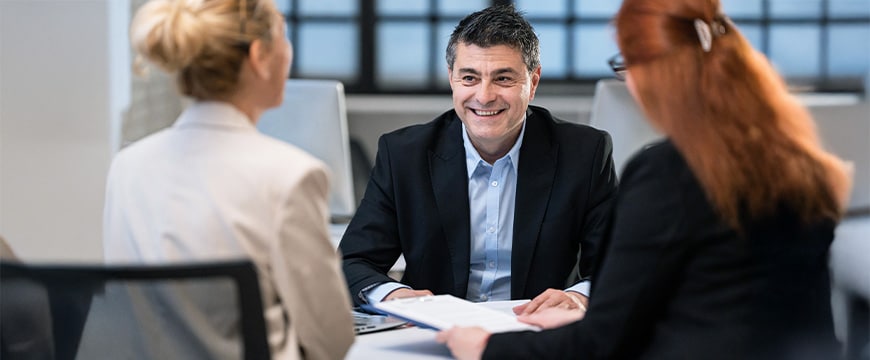 Business meeting with confident professional discussing strategies with colleagues around table.