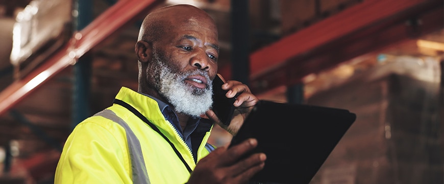 Logistics, black man and tablet with phone call for talking, coordinate shipment and confirm delivery. Supply chain, mature supervisor and digital with tech for inventory check, track stock and night