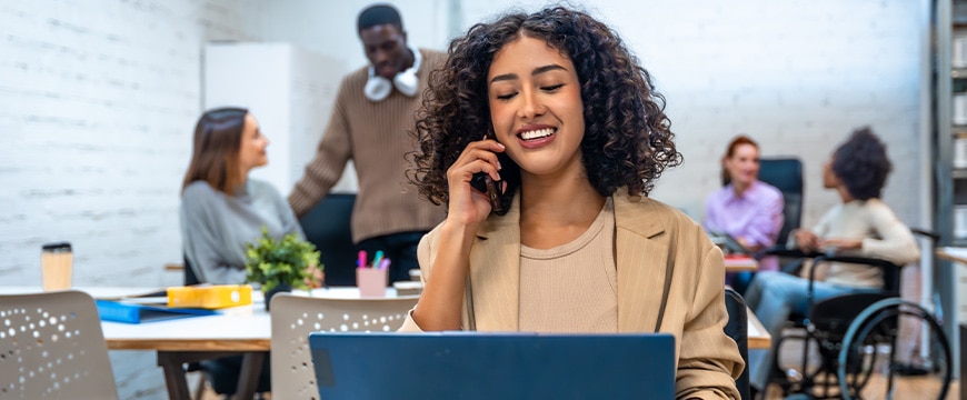 TitleCheerful woman talking to the mobile while working at coworking