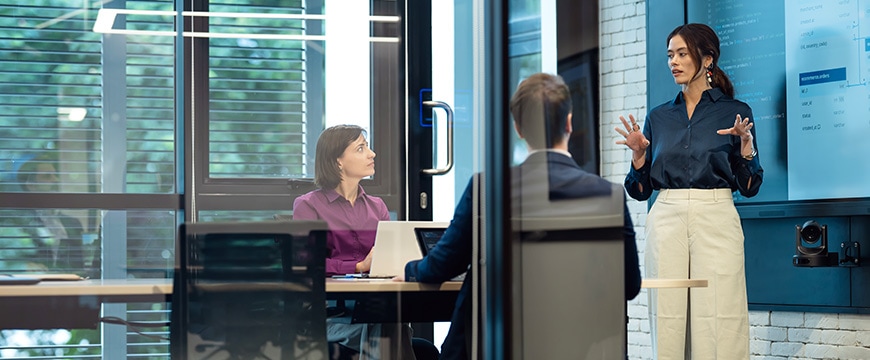 Woman in tech office speaking to coworkers.