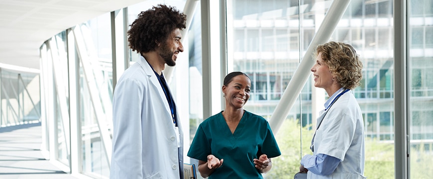 Healthcare professionals talking in modern hospital hallway.